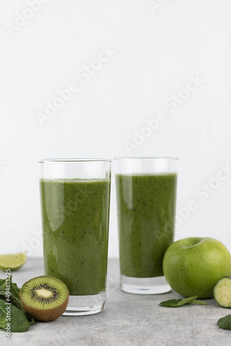 Green detox smoothie in a glass on a grey background, copy space. Green smoothie of spinach, kiwi, banana, apple in a glass. 