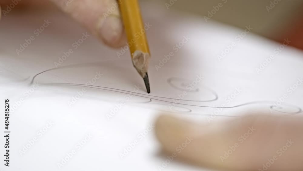 The artist drawing a flat line with a black pencil. Artists hands drawing wooden pencil writes line on paper. The artist drawing a flat line with a black pencil. Artists hands drawing wooden pencil writes line on paper.