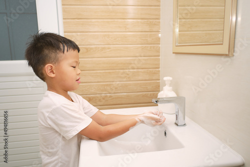 Handwashing, Cute little Asian 5 years old kindergarten boy child washing hands by himself on sink and water drop from faucet in toilet, Hygiene Habits for Kids concept, Soft and selective focus