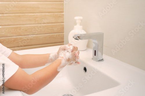 Handwashing, Cute little Asian 5 years old kindergarten boy child washing hands by himself on sink and water drop from faucet in toilet, Hygiene Habits for Kids concept, Soft and selective focus