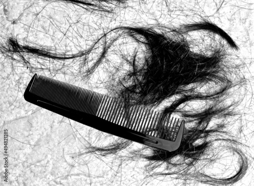 Close up image of black plastic hair comb and hairline on floor at barber shop.