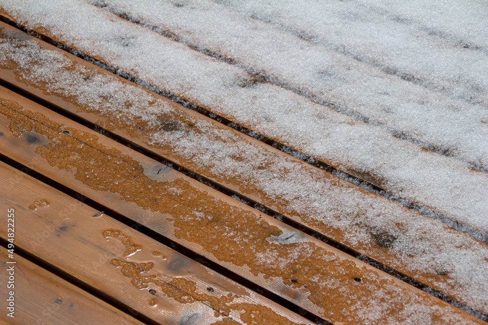 Abstract texture background of melting snow on a hardwood cedar deck in springtime