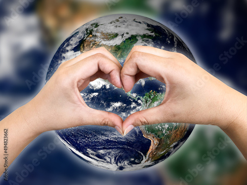 The person holding hands in a heart shape earth globe on background,  Saving and loving the planet concept, Earth image from NASA
