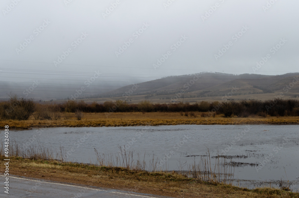 View of the river in cloudy rainy weather. Hills in the fog. View of the river in cloudy rainy weather. Hills in the fog.