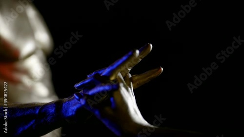 two hands with metallic golden skin touch palms, interlace fingers on a black background. close-up. blue and white light. the dark key photo