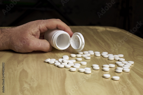 a man pours pills out of a plastic bottle on the table