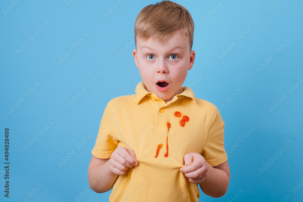 Boy showing a stain spilled from tomato sauce and spaghetti dinner on
