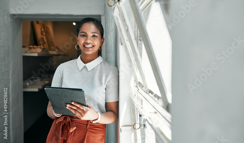 Go-getters know how to get it all done. Portrait of a young businesswoman using a digital tablet in an office.