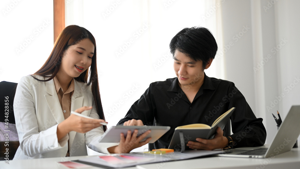 Two positive Asian business colleagues enjoy working together Two positive Asian business colleagues enjoy working together