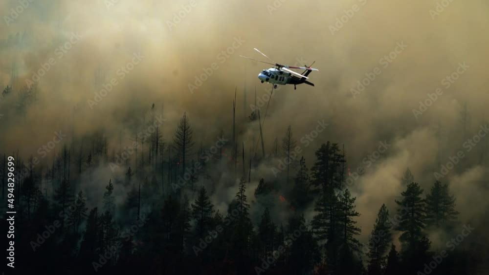 Extinguisher helicopter flying over smoking, hazy wildfire forest, in West USA Extinguisher helicopter flying over smoking, hazy wildfire forest, in West USA