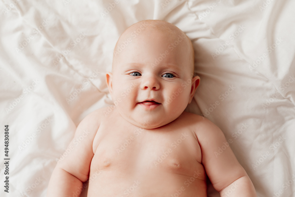 closeup portrait of a blue-eyed newborn baby lying on his back on a white sheet. happy carefree infancy. products for children, natural materials. space for text. High quality photo closeup portrait of a blue-eyed newborn baby lying on his back on a white sheet. happy carefree infancy. products for children, natural materials. space for text. High quality photo