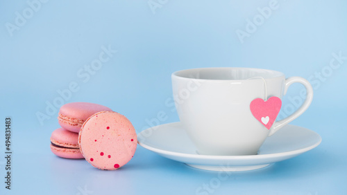 White cup with tea and pink macarons