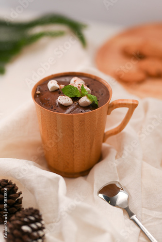 Hot dark chocolate milk with sweets marshmallow in a wooden cup.