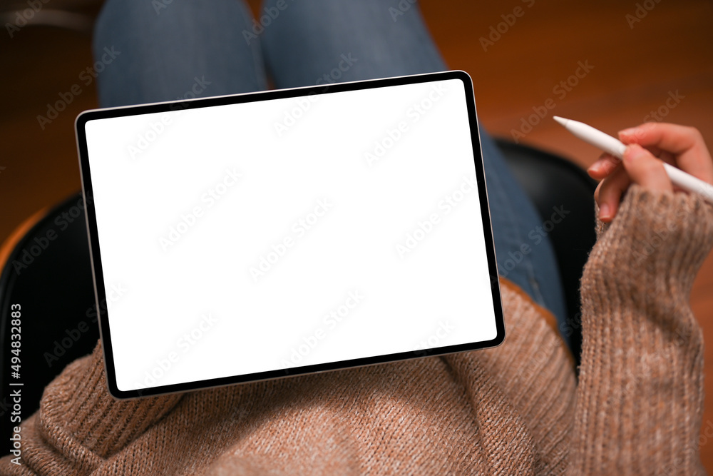 Obraz premium Relaxed young female sitting on armchair and using digital tablet