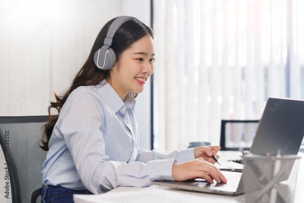 Business concept, Businesswoman in headset to meeting on video conference and taking notes on paper Business concept, Businesswoman in headset to meeting on video conference and taking notes on paper
