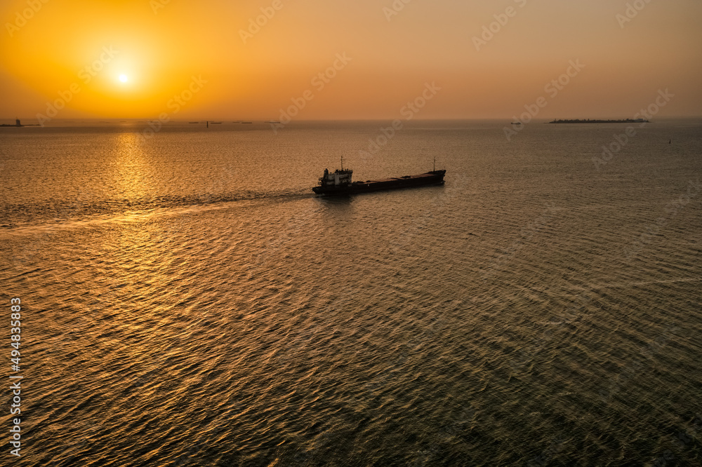 Aerial view sunset over the water channel. The cargo barge goes to the locks. Dry cargo ship transports a large volume of cargo for construction. River transport
