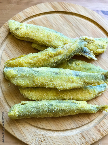 Pan fried fish on a plate. Capelin fried in oil with crispy breading.