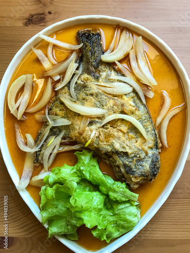 deep-fried flounder with onions and vegetables in Asian sauce on a plate.
