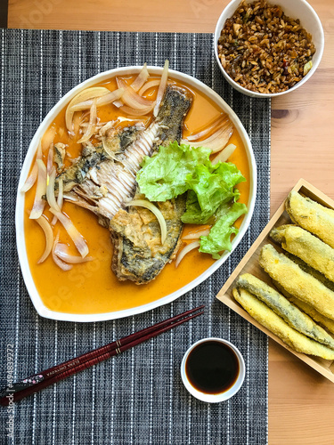 deep-fried flounder with onions and vegetables in Asian sauce on a plate.
