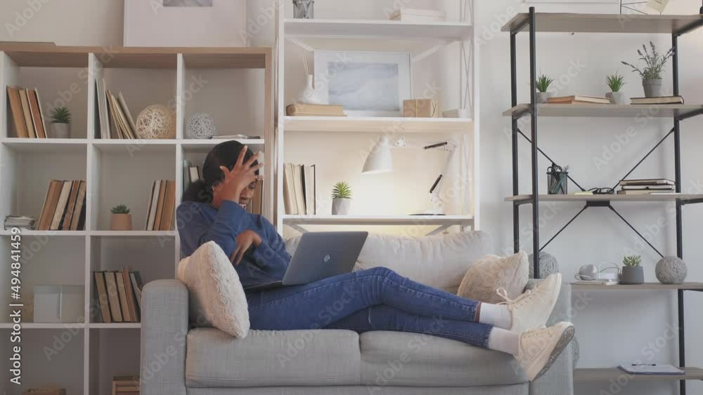 Angry video call. Online conflict. Internet bullying. Furious frustrated yelling arguing woman at laptop conference on couch at home. Angry video call. Online conflict. Internet bullying. Furious frustrated yelling arguing woman at laptop conference on couch at home.