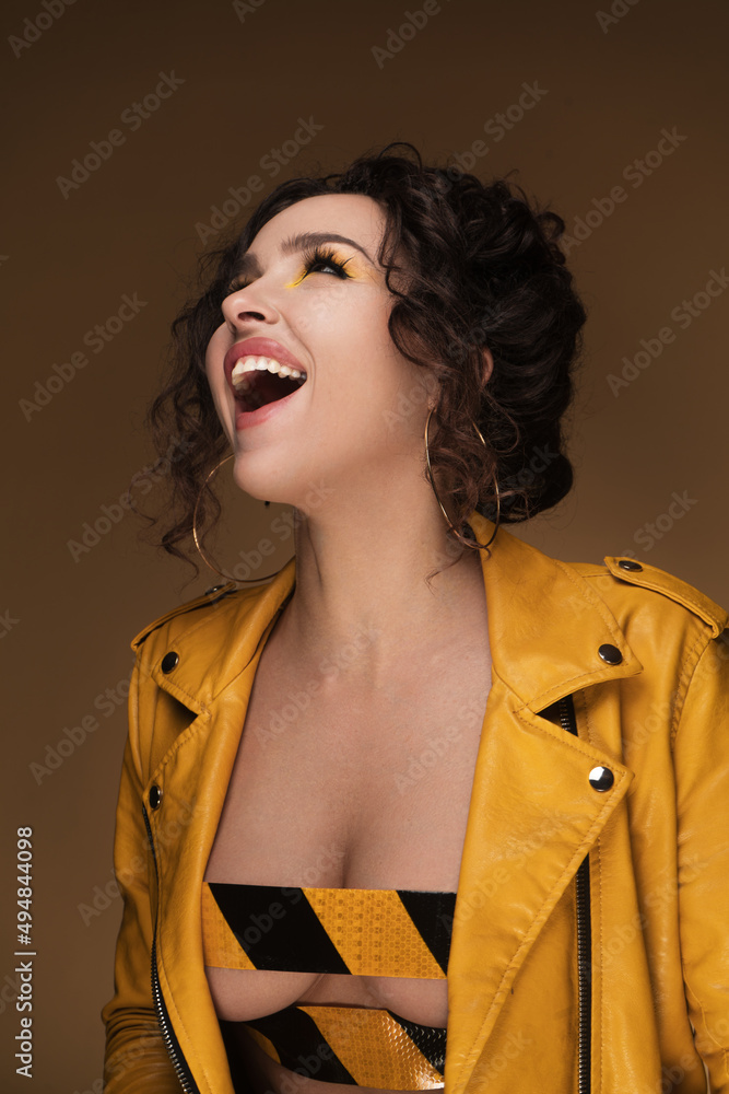 Portrait of a beautiful girl in a yellow leather jacket rewound with electrical tape on a yellow background