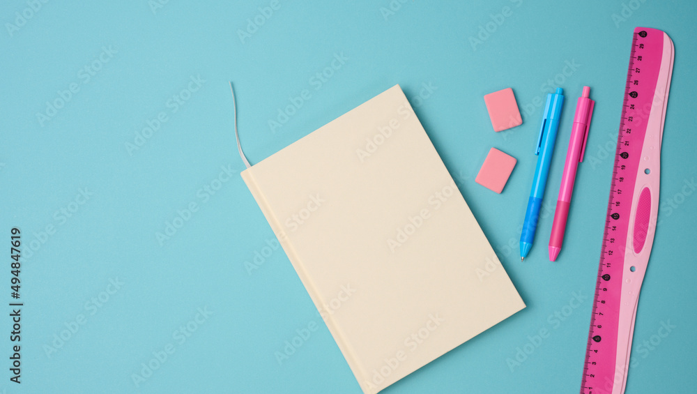 notebook and pink ruler on blue background, top view notebook and pink ruler on blue background, top view