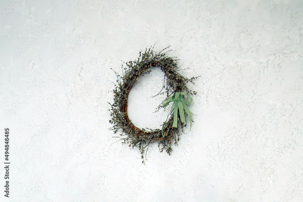 an easter wreath of dry willow branches, decorated with a green ribbon, hangs on a white old painted wall an easter wreath of dry willow branches, decorated with a green ribbon, hangs on a white old painted wall