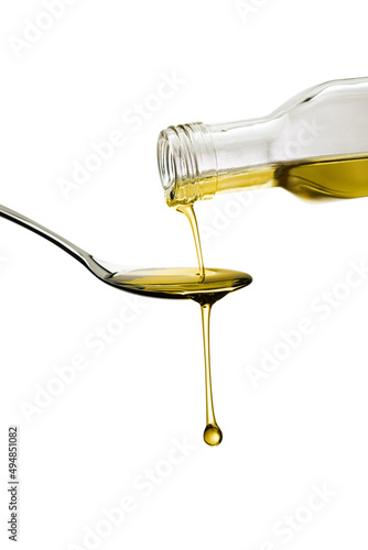 Olive oil bottle pouring oil on spoon, isolated on white background
