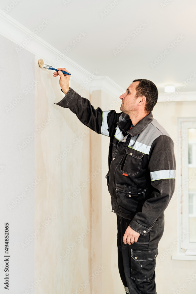 Worker applies glue to the walls before wallpapering or primer on the