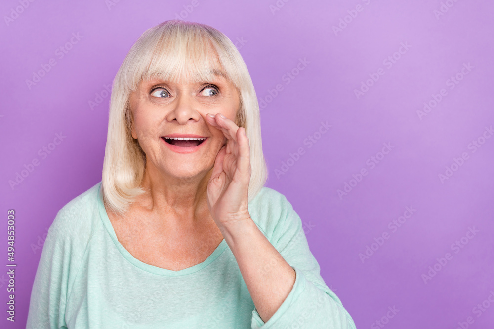 Photo of excited old lady palm open mouth share secret look empty space wear blue shirt isolated purple color background Photo of excited old lady palm open mouth share secret look empty space wear blue shirt isolated purple color background
