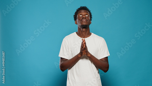 Man with faith praying to god begging for peace, believing in religion. Religious person doing prayer with hands, asking for forgiveness and gratitude. Portrait of adult with belief