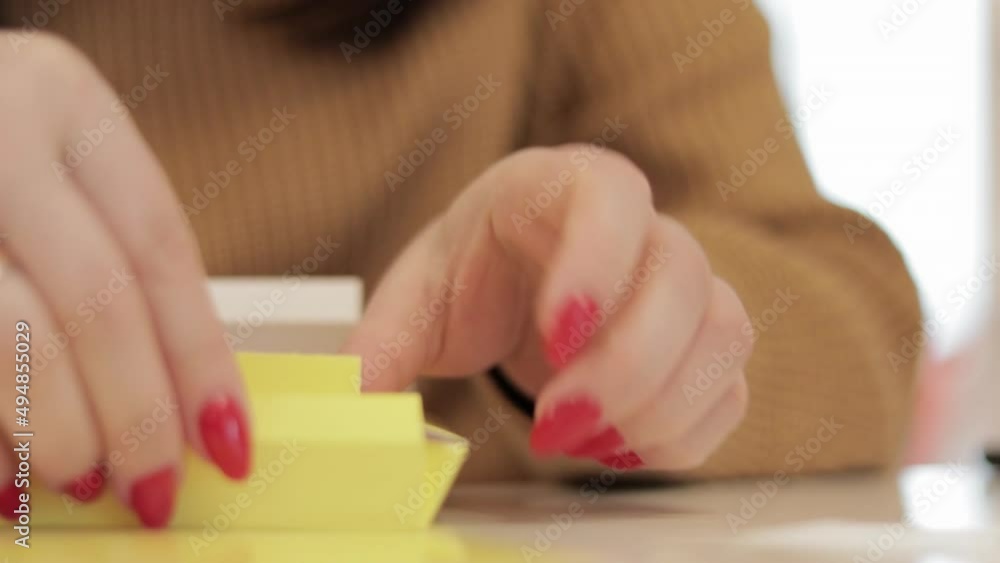 An unrecognizable woman folds a small yellow cardboard box. Production of cardboard boxes from paper. Packaging manufacturing company. Close-up of hands doing paper crafts at a creative lesson. An unrecognizable woman folds a small yellow cardboard box. Production of cardboard boxes from paper. Packaging manufacturing company. Close-up of hands doing paper crafts at a creative lesson.