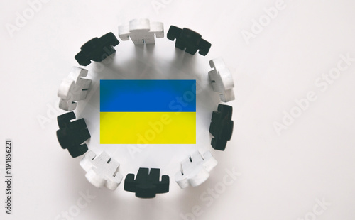 Wooden figures stand  around Ukrainian flag. Solidarity with Ukraine
