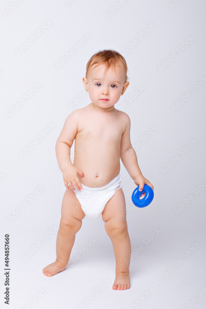 cute baby girl in a diaper stands in full height isolated on a white background