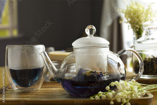 Brewed flower fragrant tea in a glass teapot on a wooden table. Clay brown cup with a teapot and white lavender flowers on a wooden table.