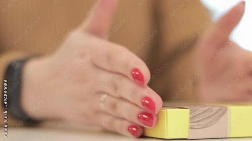 An unrecognizable woman folds a small yellow cardboard box. Production of cardboard boxes from paper. Packaging manufacturing company. Close-up of hands doing paper crafts at a creative lesson.