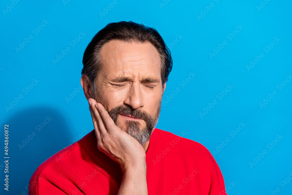 Portrait of attractive sick man touching cheek suffering tooth pain isolated over bright blue color background Portrait of attractive sick man touching cheek suffering tooth pain isolated over bright blue color background