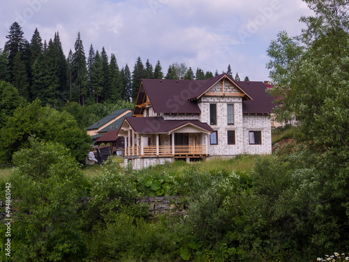 Building a house among the forest and mountains. Modern cottage in pine forest among evergreen trees in a daytime. Modern constructor building made from blocks in green woods.