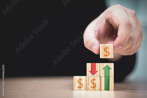 Fototapeta Naklejka Na Ścianę i Meble -  risk of currency exchange rates. The increase and decrease of profit from business results. man's hand picked up wooden block with the dollar sign and placed it on wooden block.
