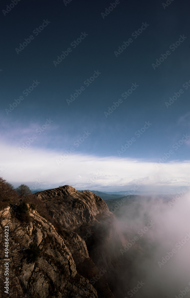 Mountains appearing behind clouds with a blue sky