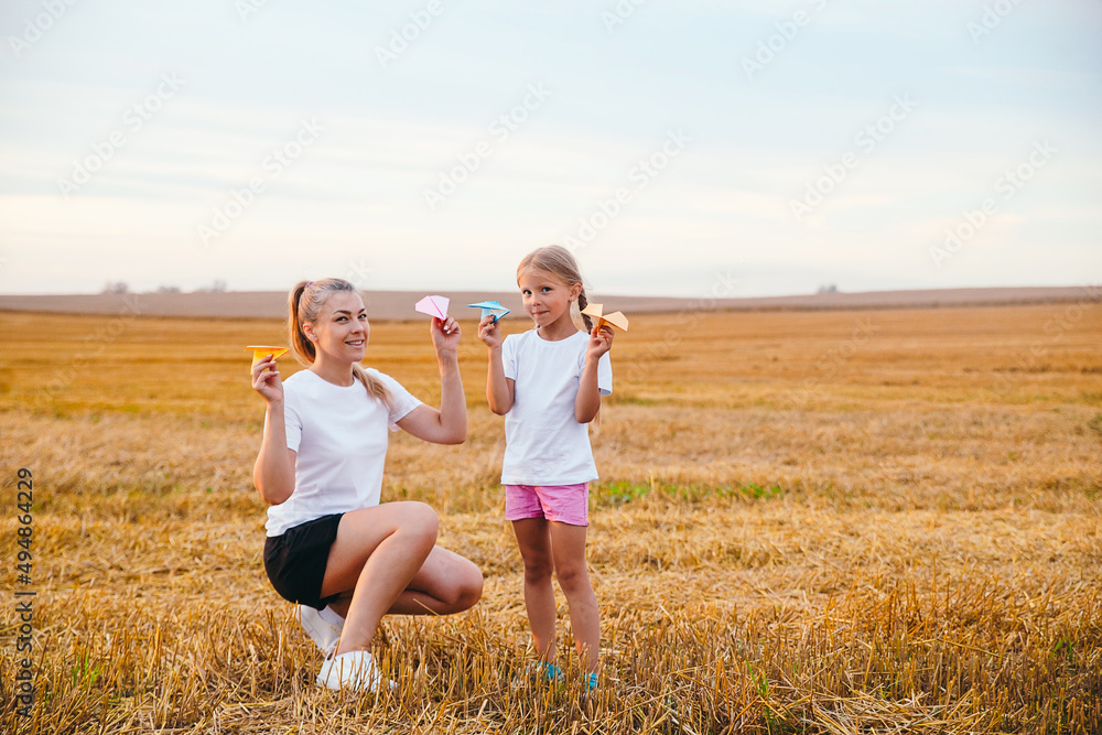 Happy mother and daughter are playing with paper airplanes outdoor Happy mother and daughter are playing with paper airplanes outdoor