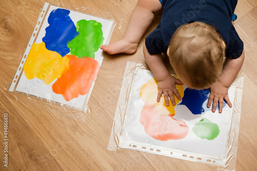 Two kids playing. painting technology. gouache on the white paper in closed plastic bag, case or hood. brothers spreading paint by hands. home made art. children game. sensoric excersise. photo