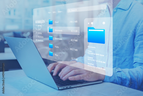 Document management system (DMS) and file manager used to browse folders on computer. Exploring directories on hard drive. Business data and process. Person working on laptop.