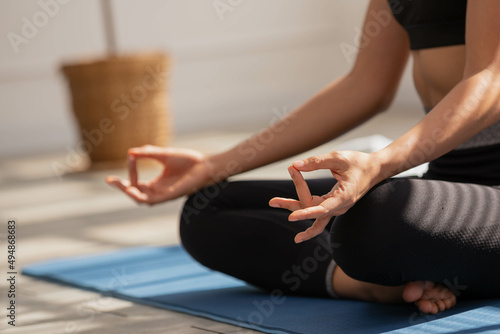 Close up Hand and face, Asian woman does morning yoga, sitting in Easy position, Sukhasana posture, and meditating.