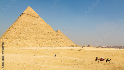 The great Pyramid complex of Giza with tourists riding camels in front of the Egyptian pyramids. Cairo, Egypt