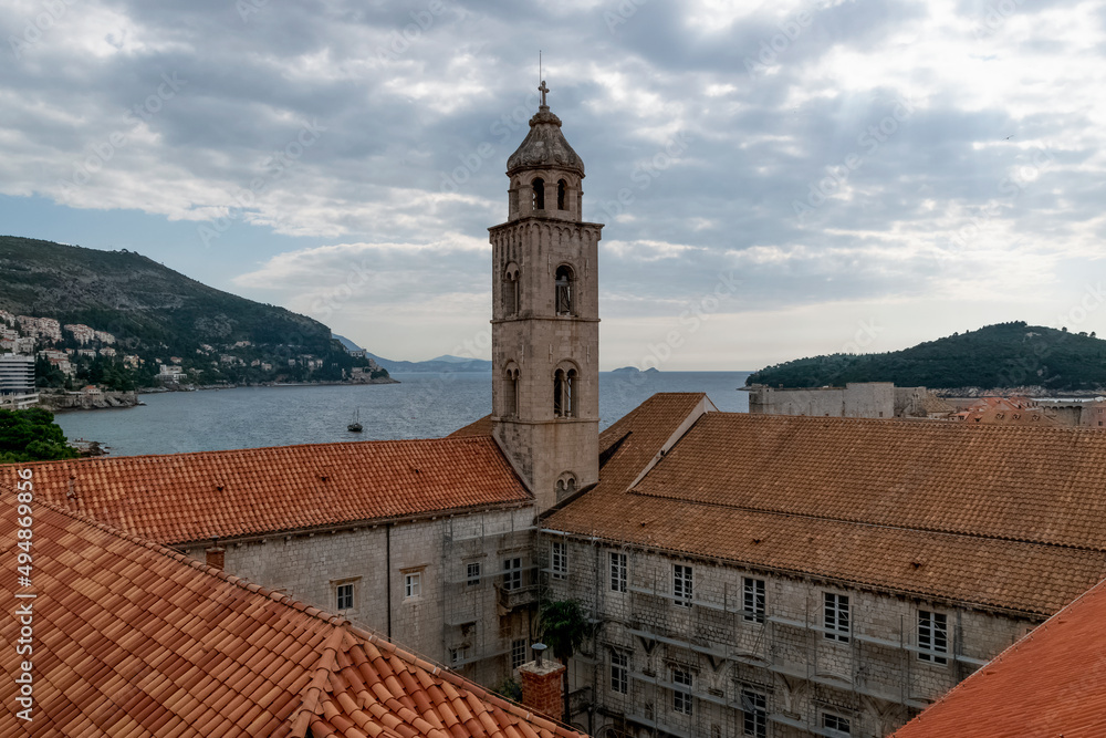 Saint Dominic Church Bell Tower and red rooftop against blue sky with clouds in the old town of Dubrovnik, Croatia.