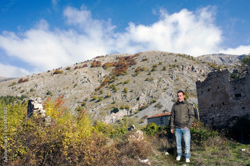 Caucasian young man near a building in the mountains. 