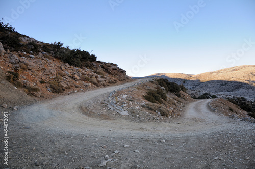 A sharp turn on a mountain gravel road. Psiloritis mountain range and the Nida plateau. Blue sky. Crete island, Greece.