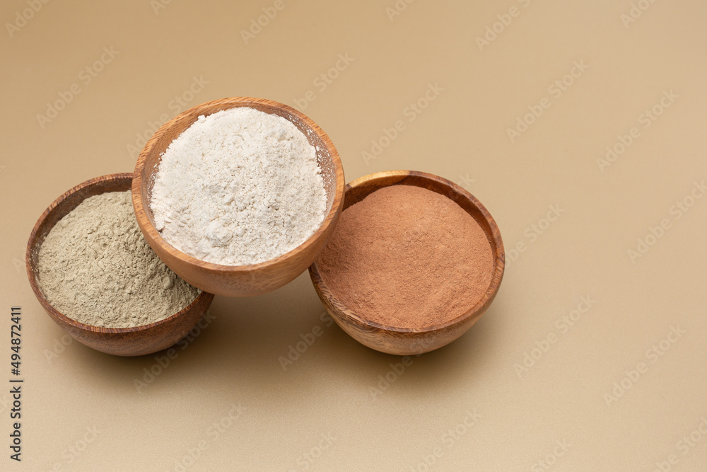 Organic green, red, white clay for facial mask on a beige background in wooden bowls. Home skin care concept.Self care.Copy space Organic green, red, white clay for facial mask on a beige background in wooden bowls. Home skin care concept.Self care.Copy space