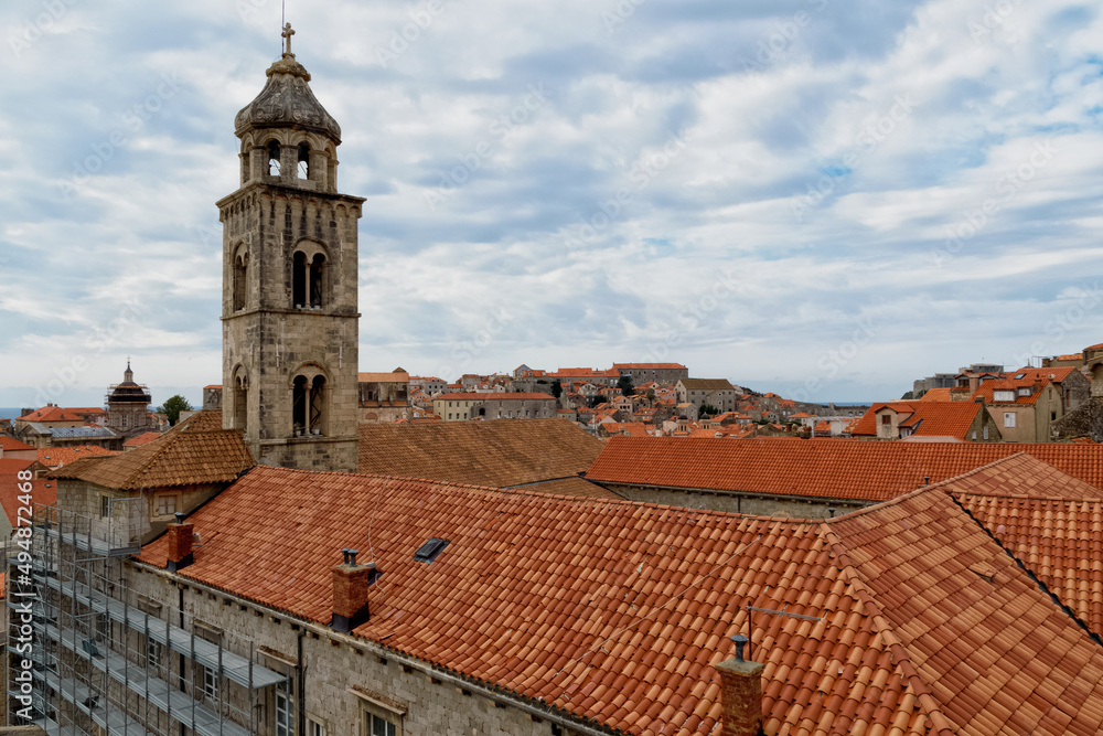 Saint Dominic Church Bell Tower and red rooftop against blue sky with clouds in the old town of Dubrovnik, Croatia.